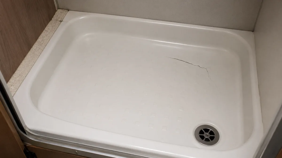 Grieta en el plato de ducha de una autocaravana antes de repararla con fibra de vidrio y resina de poliéster