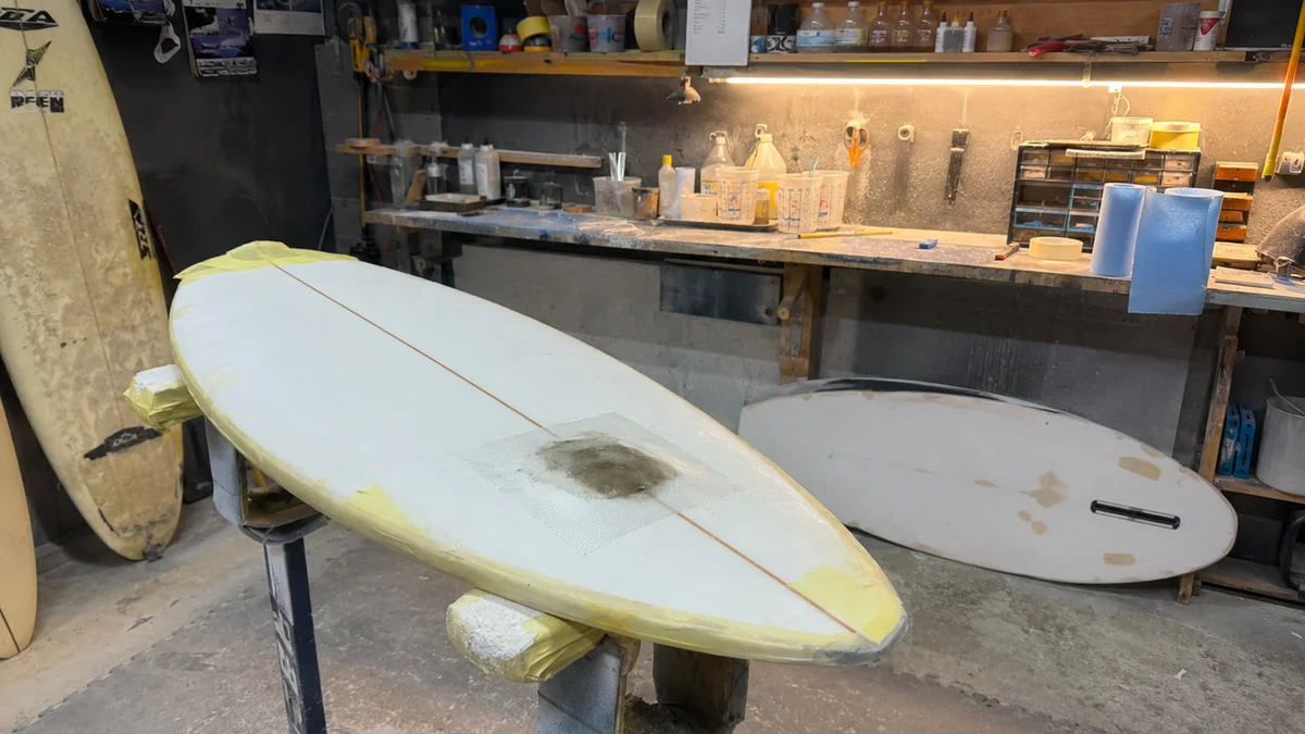 Reparación de un golpe en una tabla de surf de fibra de vidrio con parche de tejido y resina de poliéster